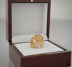 Gold ring with intricate design in a wooden jewelry box on a light gray background