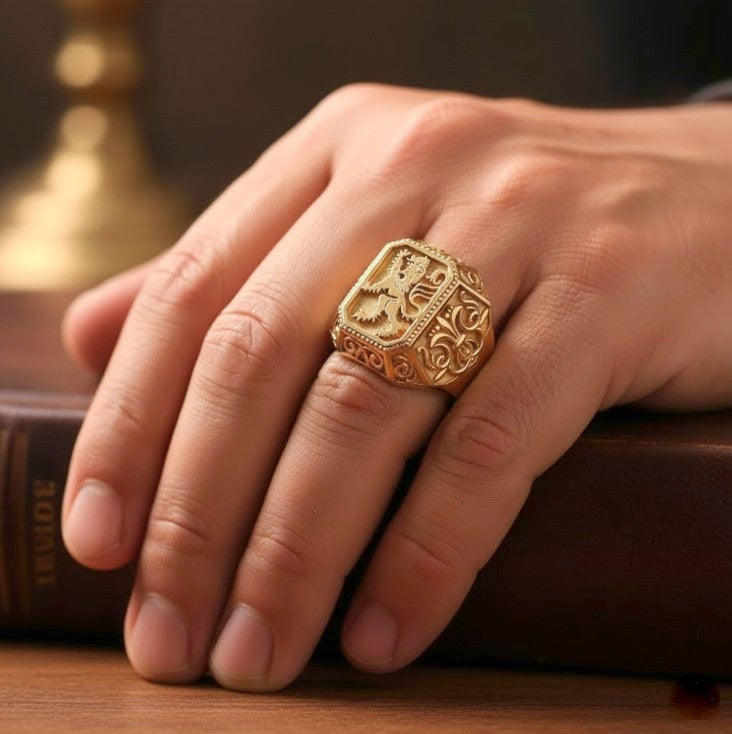 Gold ring with intricate design on a finger, placed on a wooden surface.