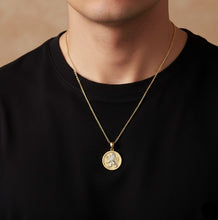 Gold necklace with a pendant worn by a person against a neutral background