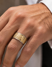 Close-up of a hand wearing two rings with intricate designs on a neutral background