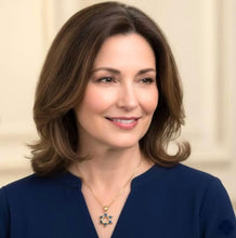 Woman wearing a blue top with a necklace against a beige background