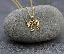 Gold necklace with a decorative pendant on a gray stone surface