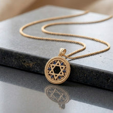 Gold necklace with a Star of David pendant on a dark surface