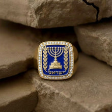 Gold ring with a blue stone and Menorah design on a stone surface