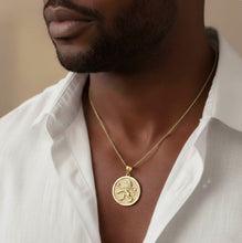 Man wearing a gold necklace with a lion emblem on a blurred background