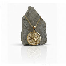 Gold necklace with a lion pendant on a gray stone surface