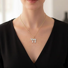 Gold necklace with a diamond pendant worn by a model against a neutral background