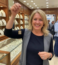 Woman holding a small gold hoshen pendant in jewelry store in Jerusalem 