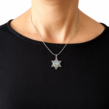 Star of David necklace with a blue gemstone worn by a person in a black 