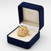 Gold ring with intricate design in a blue velvet box on a white background