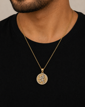 Gold necklace with a pendant worn by a person against a black background