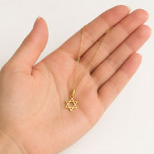 Gold necklace with a Star of David pendant held in a hand against a white background