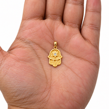 14K gold Hamsa pendant with diamond Star of David resting on an open palm.