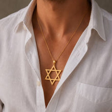 Gold Star of David necklace worn by a person in a white shirt.