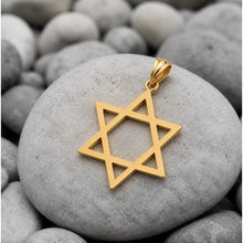Gold Star of David pendant on a gray stone surrounded by pebbles
