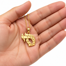 Hand holding a solid 14K yellow gold Hebrew Chai pendant with Jerusalem stone engraving