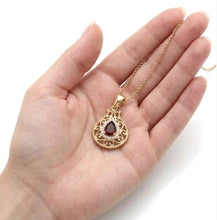 4K yellow gold pomegranate pendant with garnet on hand