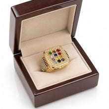 Gold ring with colored gemstones in a wooden box on a white background