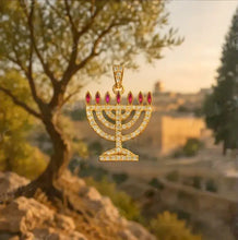 Gold menorah pendant with red gemstones against a scenic background