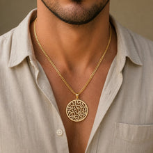 Man wearing a gold necklace with a detailed pendant against a neutral background