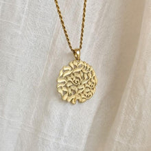 Gold necklace with a detailed pendant on a light fabric background
