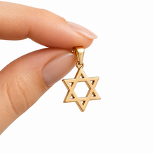 Gold Star of David pendant held between fingers on a white background