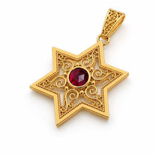 Gold star-shaped pendant with a red gemstone on a white background