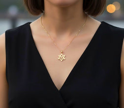 Gold necklace with a star pendant worn by a person in a black top, blurred background