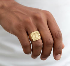 Gold ring with a menorah design on a person's finger against a white background