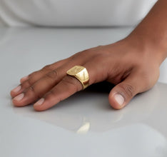 Gold ring on a hand against a neutral background