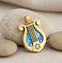 Gold pendant with blue inlay and Star of David on pebbles