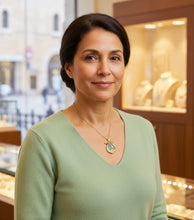 Woman wearing a green sweater and necklace with a jewelry store in the background