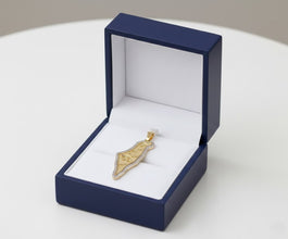 Gold pendant in a blue jewelry box on a white surface