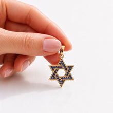 red nails holding gold jewish necklace pendant
