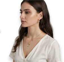 Woman wearing a gold necklace and earrings on a white background
