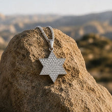 gold white  of David pendant necklace with a textured, pave-like pattern, resting on a large tan rock with a blurred desert landscape background.