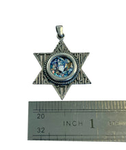 Star-shaped pendant with a blue stone and silver frame, shown next to a ruler for scale.