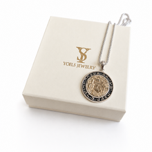 A silver chain necklace with a round coin-style pendant displayed on top of a cream-colored jewelry box. The box is branded with the gold 'Yoels Jewelry' logo.