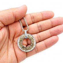 Two tone Jerusalem pendant necklace with gold city details and silver frame displayed on a hand