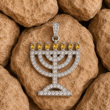 gold Menorah pendant with yellow stones on a stone background