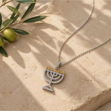 Silver Menorah pendant necklace on a stone surface with olive branch