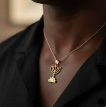 Gold Menorah pendant necklace on a person wearing a black blazer.