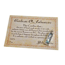 A vintage-style certificate of authenticity for a Holy of Holies pendant, featuring an ornate beige border and text detailing a 3000-year-old Roman glass piece. The certificate is signed 'Yoels Jewelry' and includes a small photo of the blue and silver pendant.