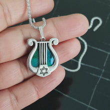 A 925 sterling silver harp pendant featuring a green eilat stone in the center, with star of david pendant on the side.