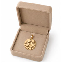 Gold necklace with a intricate pendant held in a hand on a white fabric background