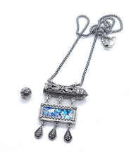 Silver necklace with a blue gemstone pendant on a white background