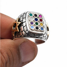 Silver ring with colorful gemstones on a finger against a white background