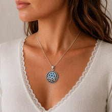 Close-up of a woman wearing a silver necklace with a blue pendant.
