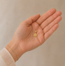 Gold star-shaped pendant held in a hand against a beige background
