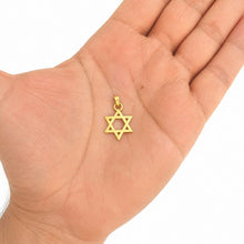 Gold Star of David pendant held in a hand on a white background